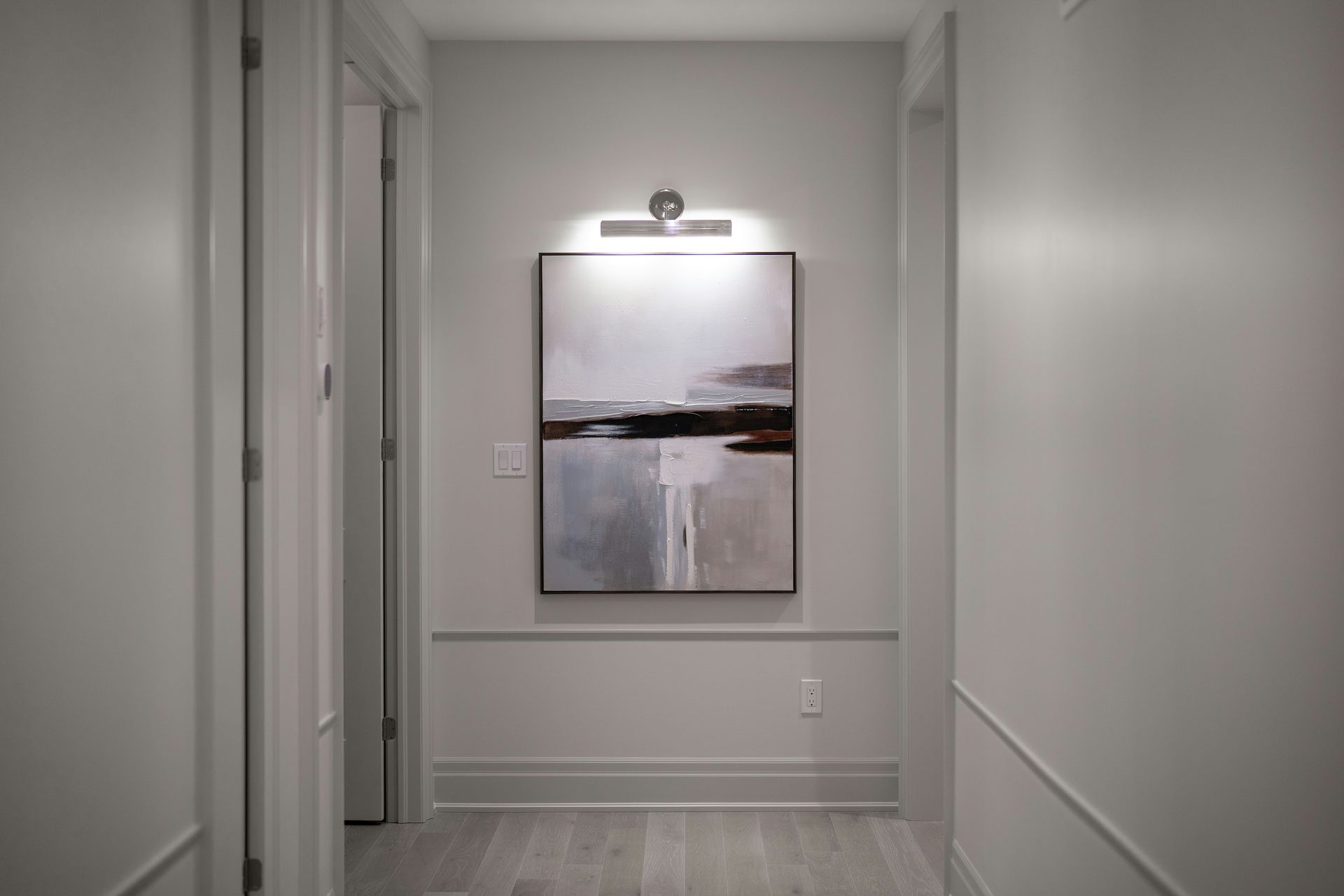 A narrow hallway with abstract art and wainscoting.