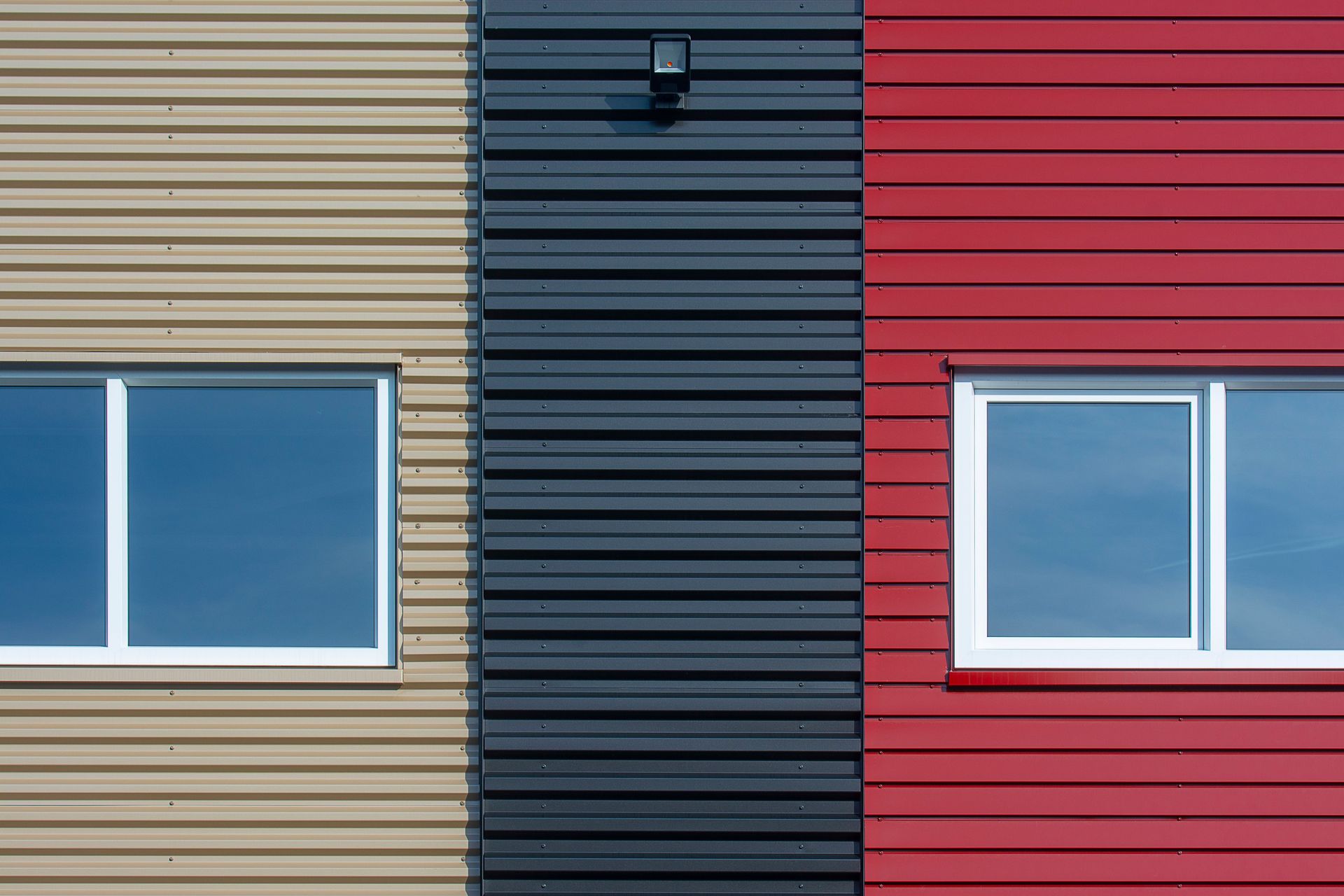 Close-up of a modern facade featuring colorful corrugated panels with windows.
